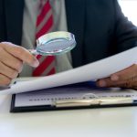 Lawyer use magnifier glass look to the paper for inspection examination to the law case