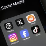 Assorted social media apps, including Threads, X, Reddit, Instagram, Facebook, and TikTok, are seen on an iPhone.