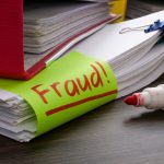 A folder and stack of papers about finances or taxes with an inscription fraud.