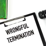 Green book, judge gavel and white paper written with WRONGFUL TERMINATION