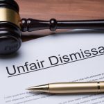 Documents Of Unfair Dismissal With Gavel And Pen On Wooden Desk In A Courtroom