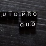 Quid Pro Quo in Latin on wooden cubes. On table background