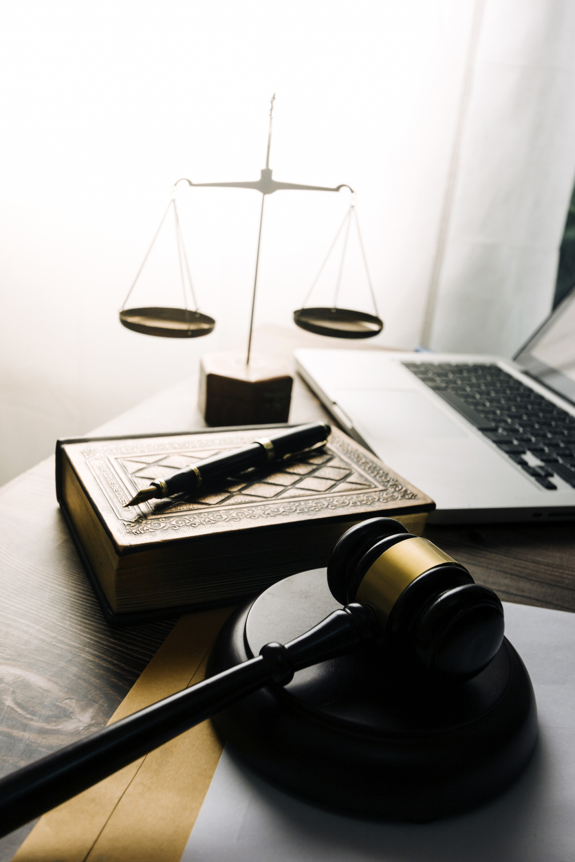 Justice and law concept.Male judge in a courtroom with the gavel, working with, computer and docking keyboard, eyeglasses, on table in morning light