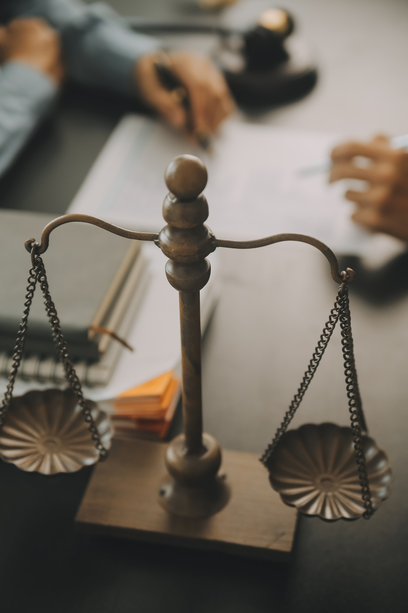 Business and lawyers discussing contract papers with brass scale on desk in office. Law, legal services, advice, justice and law concept picture with film grain effect